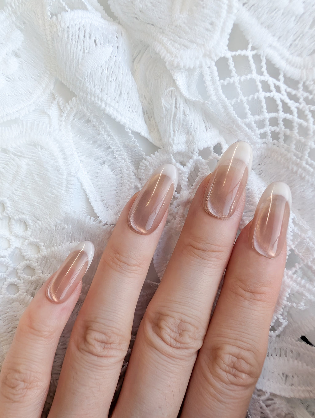 Close-up of a hand with clear nail polish on a textured white fabric background