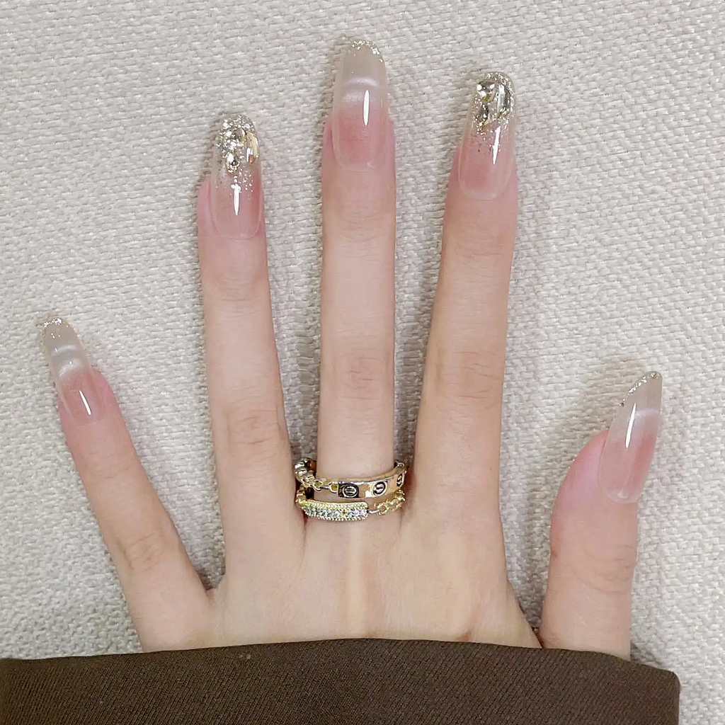 Hand with long, decorated nails and a gold ring on a textured background