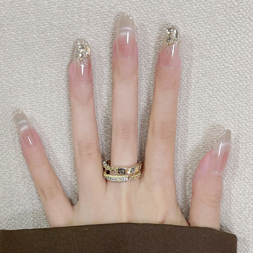 Hand with long, decorated nails and a gold ring on a textured background
