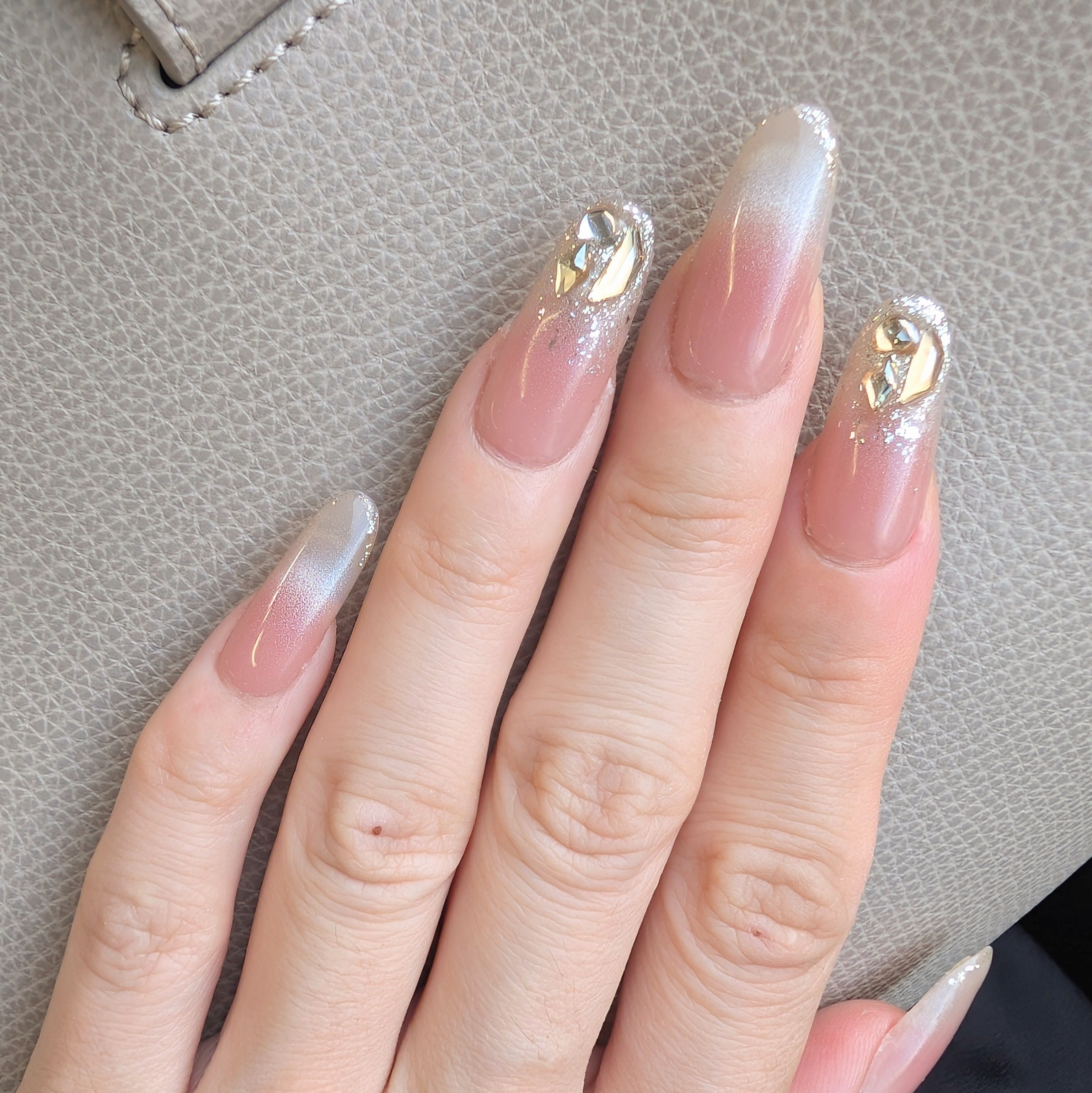 Close-up of a hand with decorative nails against a textured surface