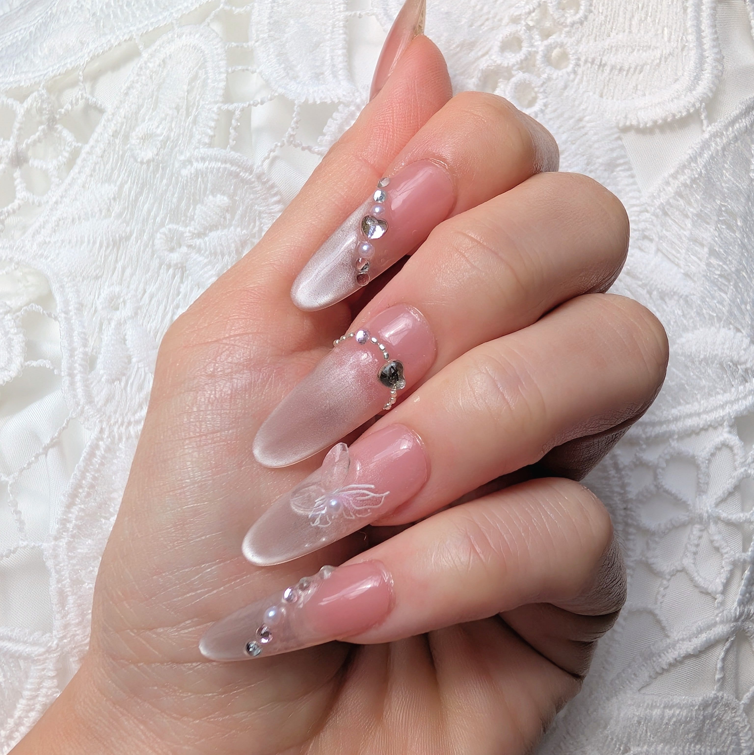 Hand with decorative nails on a white lace background