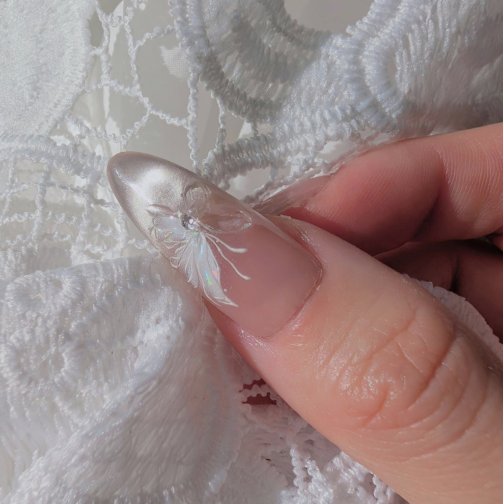 Close-up of a hand holding a small decorative item against white lace fabric